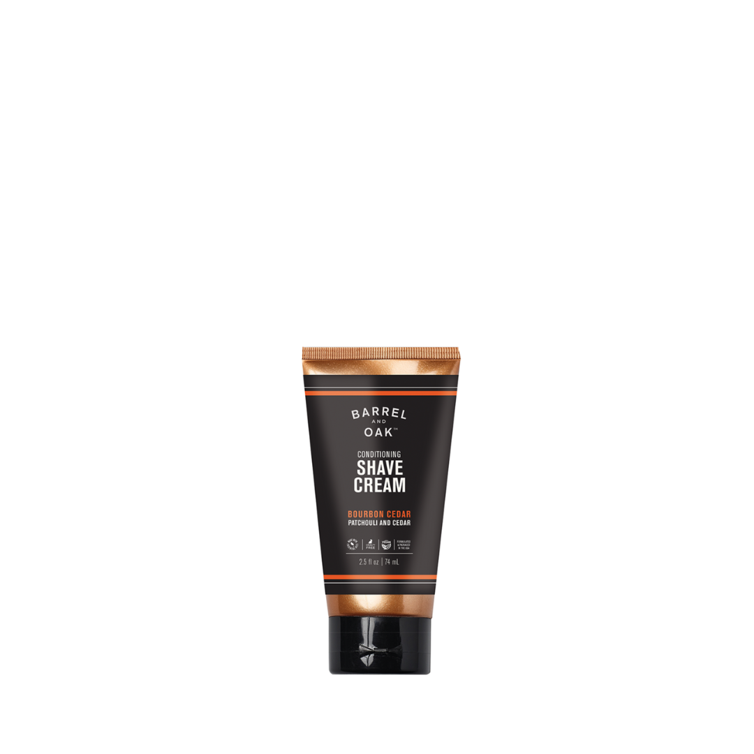 A 2 fl oz. tube of Conditioning Shave Cream - Bourbon Cedar stands upright against a white background, featuring organic hemp seed oil and a black and bronze design.