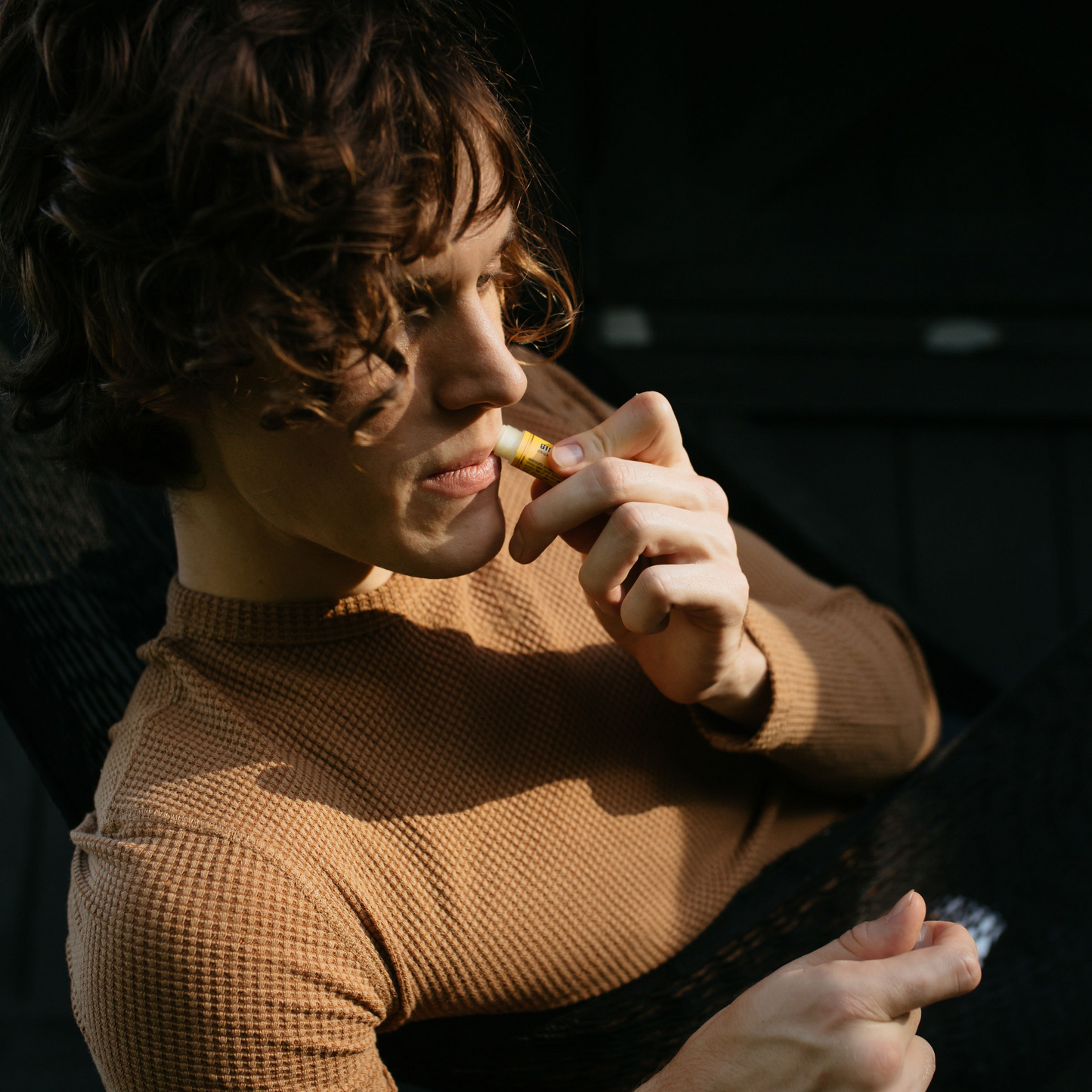 Model applying Olive Oil Lip Balm - Ginger Citrus to their lips