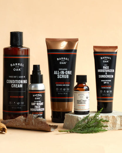 The SPF 15 Moisturizer - Bourbon Cedar (2.25 fl oz.) is shown on a beige surface, styled with wood and greenery details.