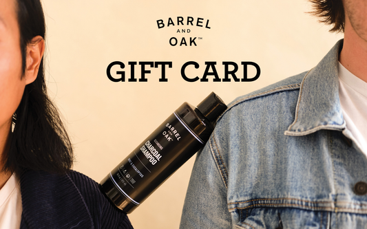 A person in a denim jacket and another in a dark sweater pose with a Barrel & Oak Gift Card displayed above them on a beige background.
