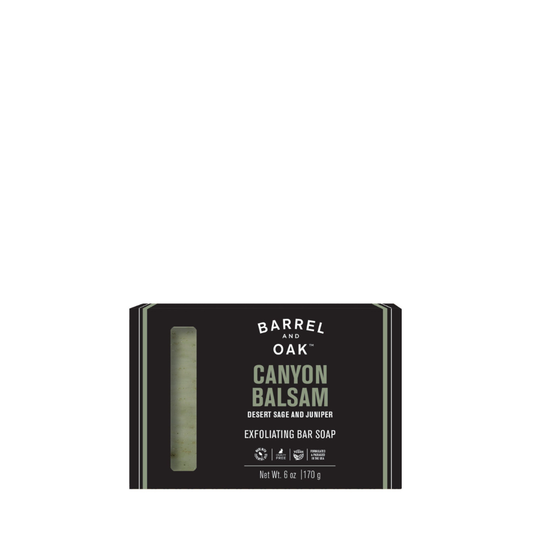 A 6oz Exfoliating Soap Bar - Canyon Balsam features dark packaging with a window revealing green soap inside. Made with walnut shell powder and scented with Desert Sage and Juniper. Net weight: 6 oz (170 g).