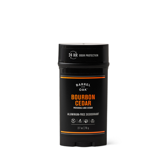 A black stick of Aluminum Free Deodorant - Bourbon Cedar 2.7 oz., featuring white and orange text on the label and formulated for sensitive skin, stands upright against a plain white background.