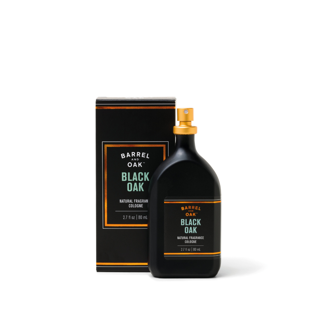 A black bottle of Natural Fragrance Cologne - Black Oak 2.7 fl oz with a gold spray nozzle stands by its matching black and gold box, featuring an earthy, warm oak scent made with natural essential oils.