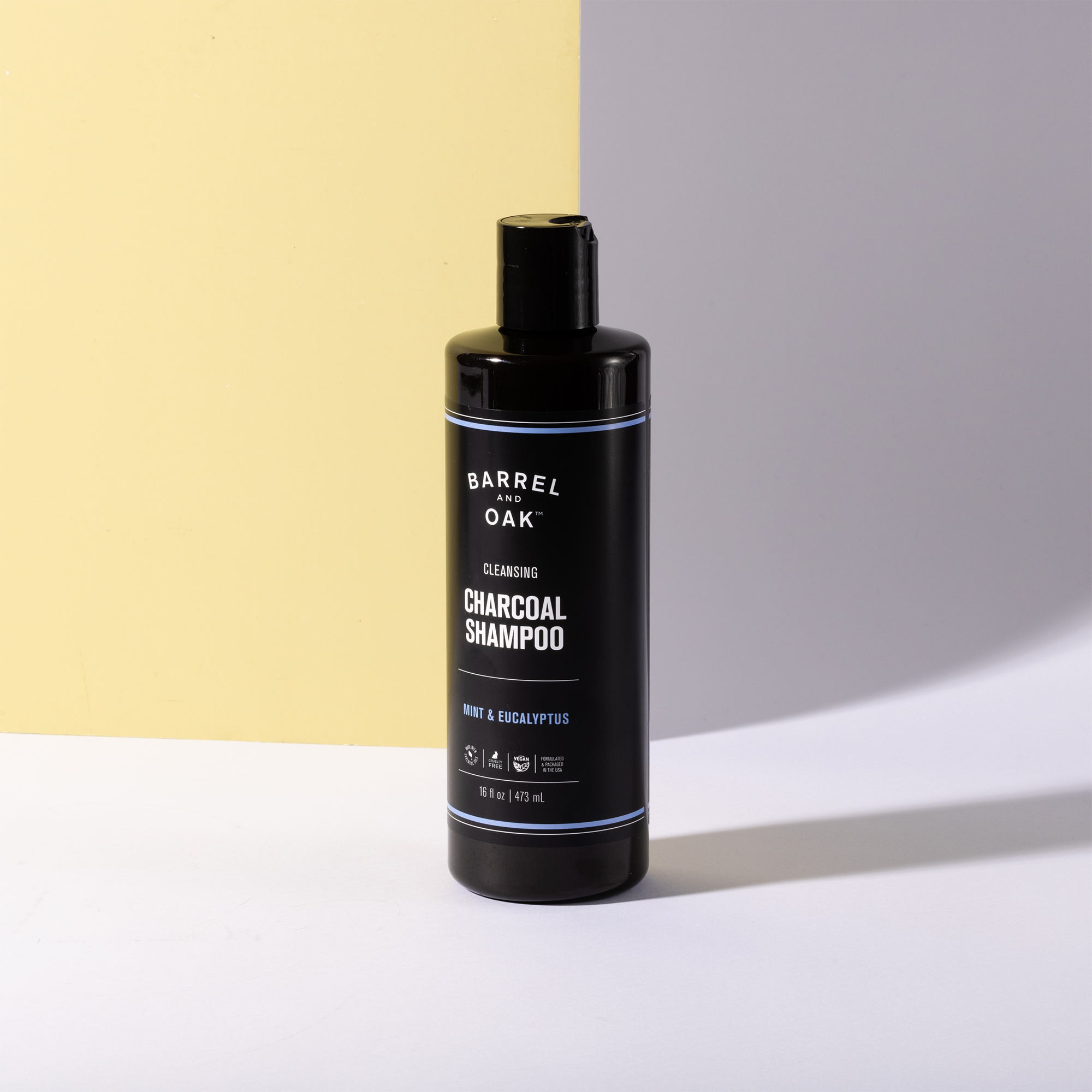 A black bottle of Cleansing Charcoal Shampoo - Mint & Eucalyptus 16 oz., vegan and cruelty-free, offers a refreshing scalp detox and organic hair cleansing.
