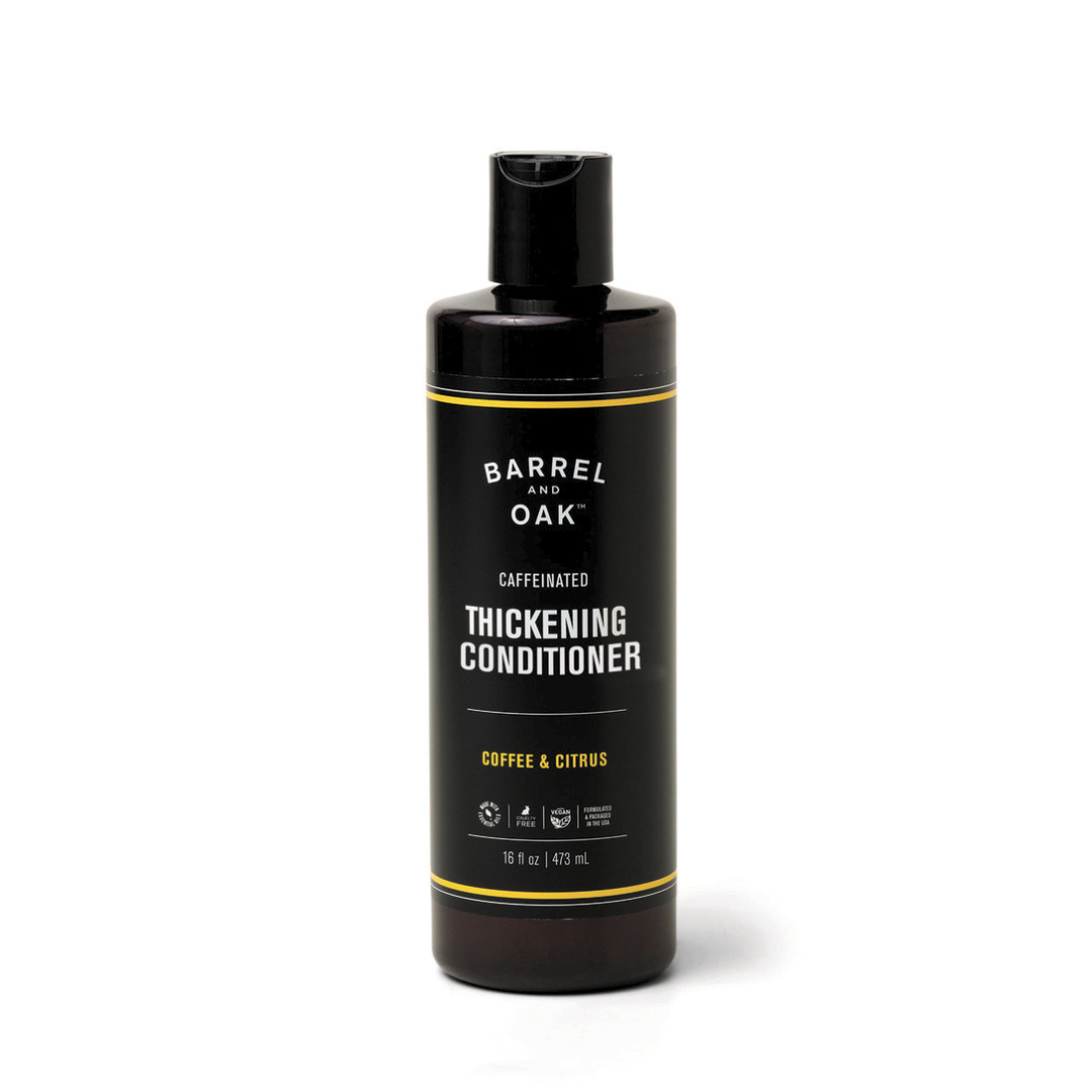 A black bottle of Caffeinated Thickening Conditioner - Coffee & Citrus 16 oz, featuring a flip-top cap and enriched with organic bergamot oil for thicker-looking hair, is set against a plain white background.