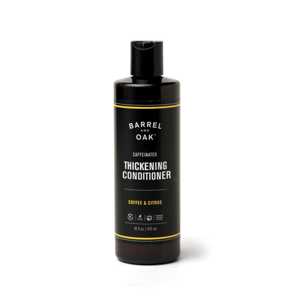 A black bottle of Caffeinated Thickening Conditioner - Coffee & Citrus 16 oz, featuring a flip-top cap and enriched with organic bergamot oil for thicker-looking hair, is set against a plain white background.