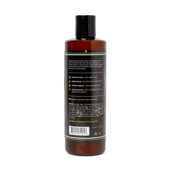 A brown plastic bottle with a black flip-top lid, shown from the back. The label lists features like organic witch hazel and shea butter, but the brand and "2 in 1 Shampoo - Canyon Balsam" product name are not visible.