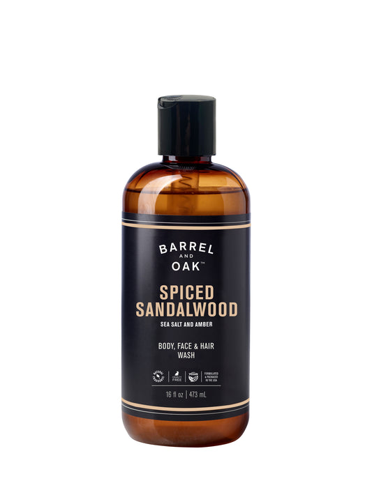 A 16 fl oz brown plastic bottle of Hair, Face, and Body All In One Wash – Spiced Sandalwood, with essential oils, sea salt and amber scent; features a black label, flip cap; for use on body, face, and hair.